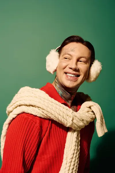A cheerful young man adorned with tattoos enjoys a moment indoors, dressed warmly and smiling. — Stock Photo