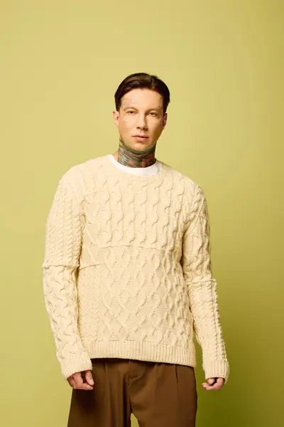 The young man flaunts his unique tattoos in a cozy sweater, radiating style and confidence. — Stock Photo