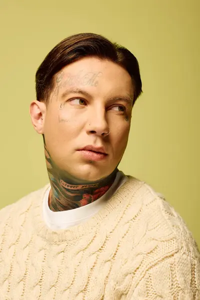 A young man with distinctive tattoos gazes off thoughtfully, showcasing his unique style. — Stock Photo