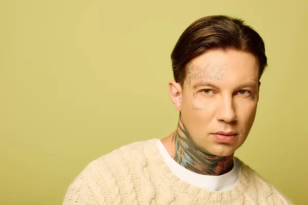 A young man showcases his unique tattoos while engaging the camera with a thoughtful expression. — Stock Photo