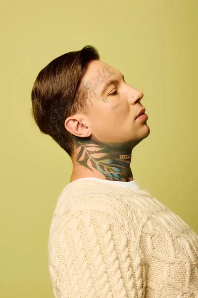 A young man showcases intricate tattoos on his neck while gazing thoughtfully to the side. — Stock Photo