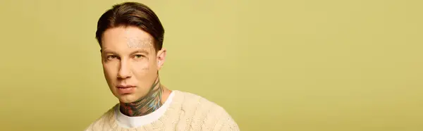 Un giovane uomo mostra i suoi tatuaggi dettagliati mentre guarda con attenzione lo spettatore, irradiando stile. — Foto stock