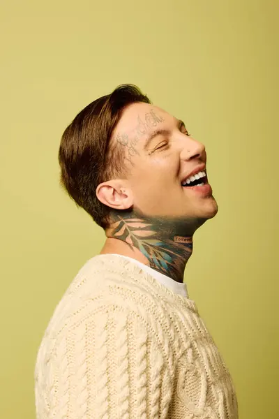 El joven muestra sus tatuajes mientras sonríe alegremente frente a un brillante telón de fondo. - foto de stock