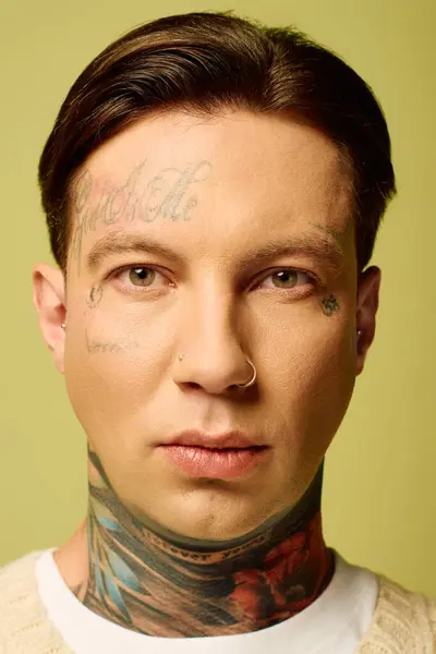 The young man showcases intricate tattoos on his face and neck while posing confidently. — Stock Photo