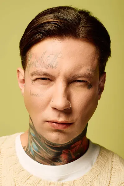 This young man showcases his intricate facial and neck tattoos while looking directly ahead. — Stock Photo