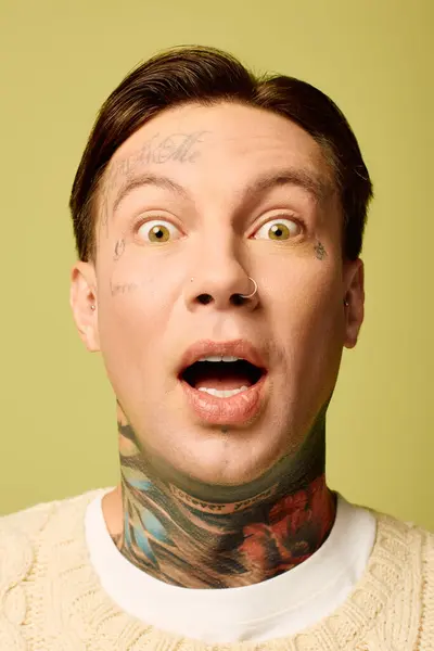 A young man with striking tattoos displays an expression of shock and excitement. — Stock Photo