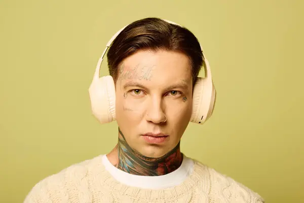 Der junge Mann zeigt seine einzigartigen Tätowierungen, während er Musik mit Kopfhörern genießt. — Stockfoto