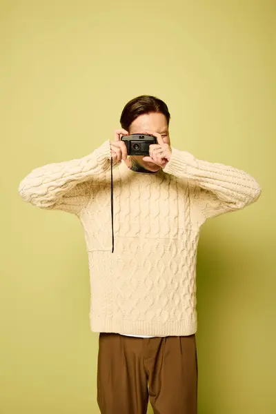 A youthful man with tattoos poses playfully while taking pictures in a soft, warm sweater. — Stock Photo