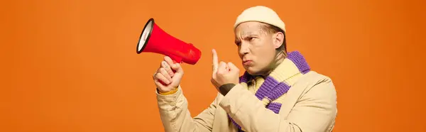 Expressive young man with tattoos passionately gestures while holding a megaphone, radiating energy. — Stock Photo