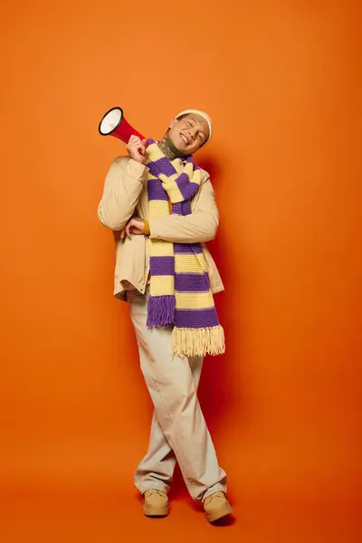 A young man joyfully poses with a megaphone, showcasing his tattoos and vibrant attire. — Stock Photo