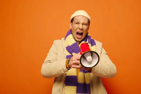 Ein junger Mann mit Tätowierungen spricht begeistert durch ein Megafon, umgeben von leuchtenden Farben. — Stockfoto