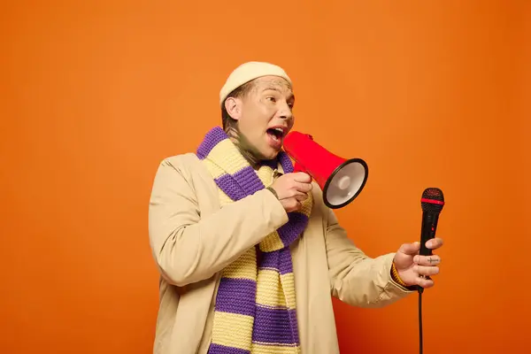 The young man enthusiastically addresses an audience while holding a bright megaphone. — Stock Photo