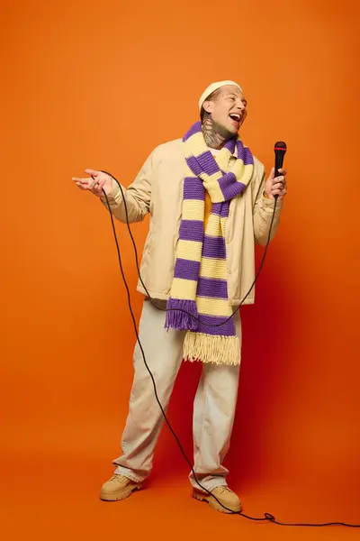 The young man smiles widely, dressed casually, as he passionately performs with a mic in hand. — Stock Photo