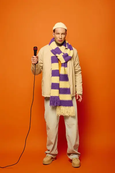 A young man in casual attire stands with a microphone, creating an artistic vibe. — Stock Photo