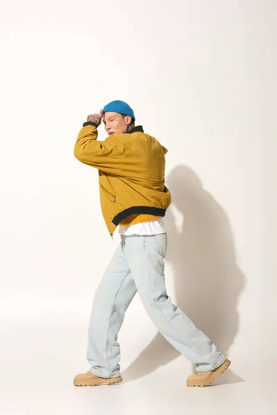 The young man showcases his unique tattoos while striking a vibrant pose in relaxed clothing. — Stock Photo