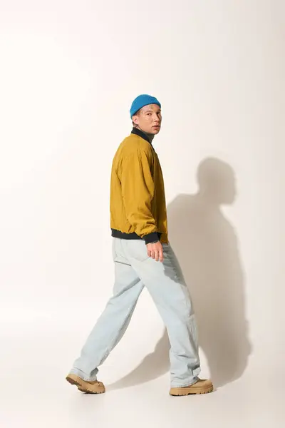 A tattooed young man walks confidently in a stylish jacket and casual pants. — Stock Photo