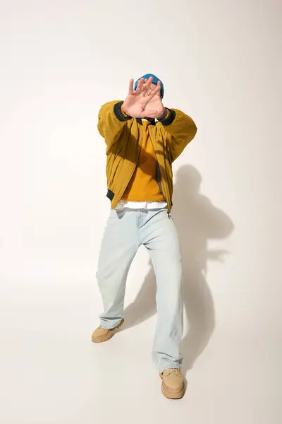 A young man with vibrant tattoos strikes a playful pose while wearing a colorful jacket. — Stock Photo