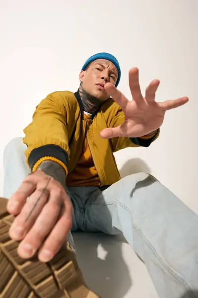 A tattooed young man in a colorful outfit demonstrates confidence and style in a studio. — Stock Photo