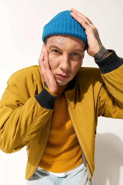 A tattooed young man ponders deeply, resting his face in his hand while dressed stylishly. — Stock Photo