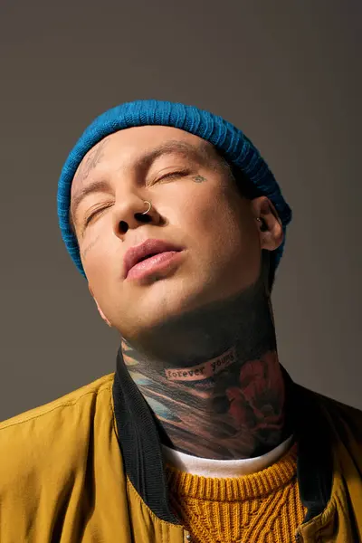 A young man with intricate tattoos wears a beanie, immersed in a moment of introspection. — Stock Photo