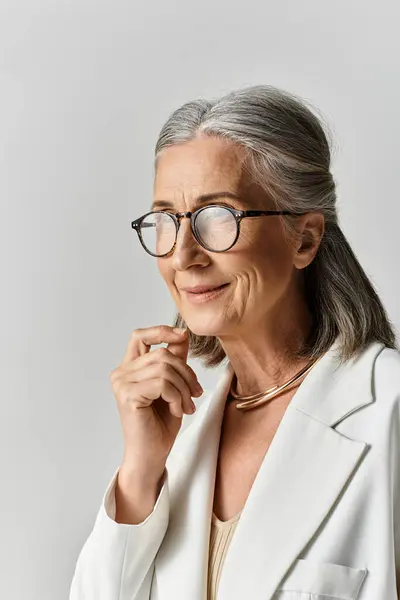 Una bella donna matura con i capelli d'argento posa con grazia in un abito bianco chic, mostrando la sua eleganza. — Foto stock