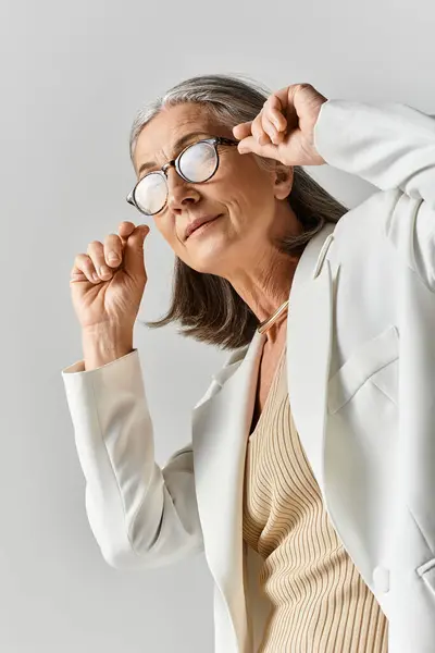 Una hermosa mujer madura muestra su elegancia en un traje blanco a medida, exudando confianza y estilo. - foto de stock