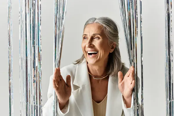 A cheerful woman with grey hair embraces the holiday spirit, spreading joy during Christmas celebrations. — Stock Photo