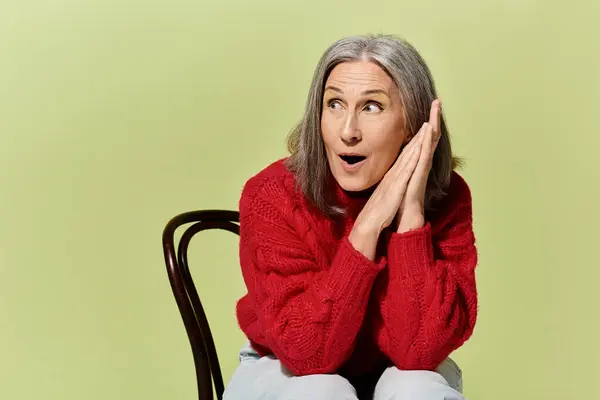 An elegant mature woman with grey hair shares a playful moment, showcasing seasonal fashion in a cozy sweater. — Stock Photo