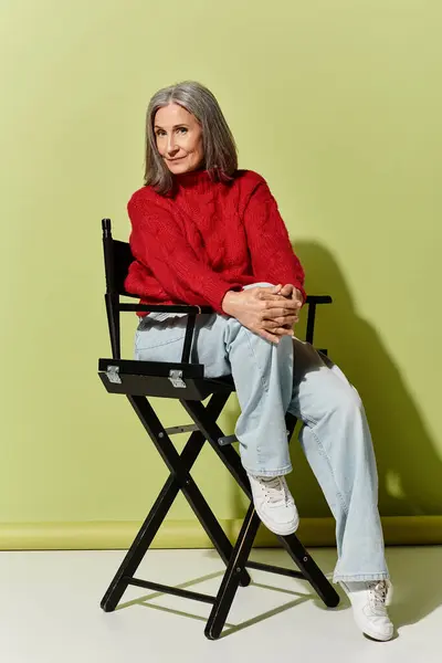 Eine selbstbewusste reife Frau mit grauen Haaren posiert in einem gemütlichen roten Pullover und präsentiert ihren Winterstil. — Stockfoto