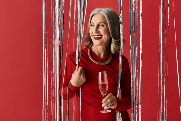 A beautiful mature woman with grey hair joyfully holds a glass, celebrating Christmas and New Year. — Stock Photo