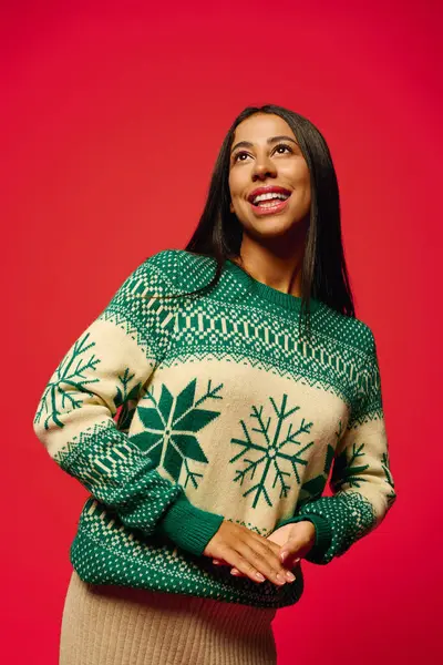 A cheerful young woman playfully poses in a cozy sweater adorned with winter patterns. — Stock Photo