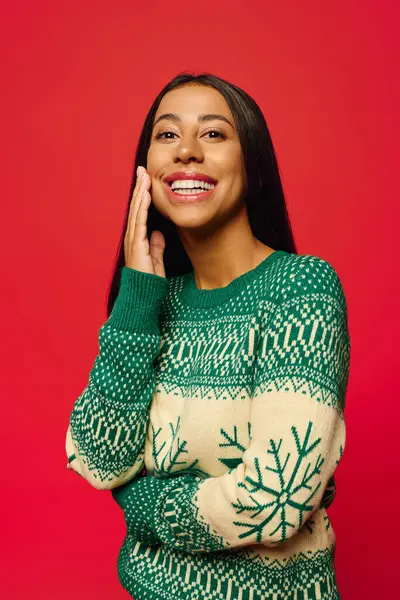 A joyful young woman wearing a holiday sweater expresses happiness with a warm smile. — Stock Photo