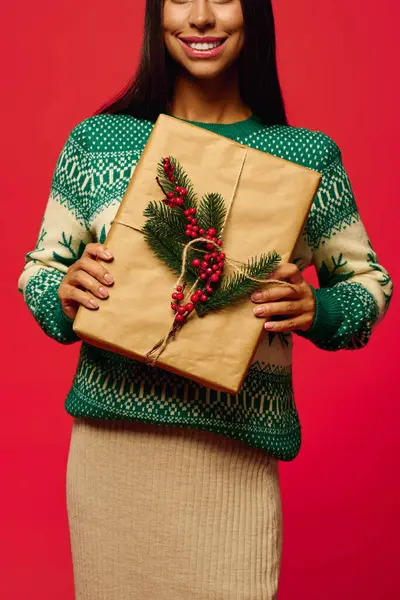 Eine junge Frau strahlt, während sie ein schön verpacktes Weihnachtsgeschenk in der Hand hält. — Stockfoto