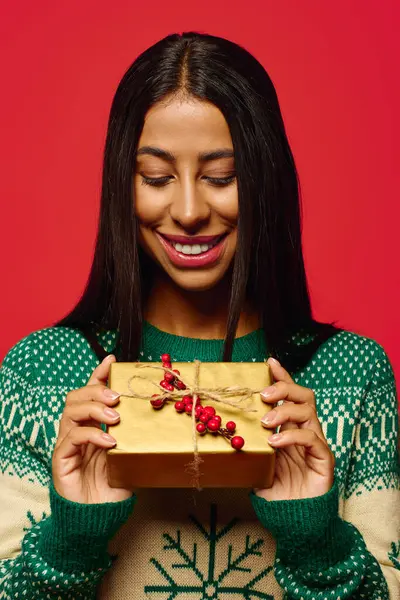 With a joyful smile, a young woman holds a festive present adorned with festive decorations. — Stock Photo