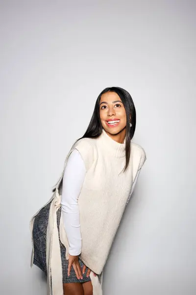 A young woman with long hair playfully poses in her stylish outfit, radiating joy. — Stock Photo