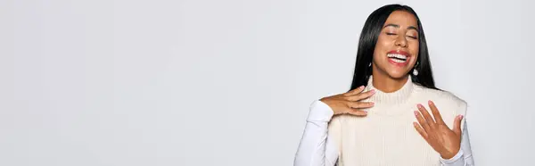 Веселая молодая женщина выражает счастье и уверенность в себе в светлой обстановке. — стоковое фото