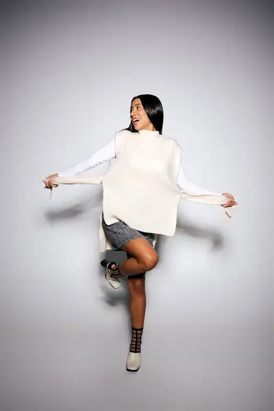 In a contemporary studio, a stylish woman poses playfully while demonstrating her outfit. — Stock Photo