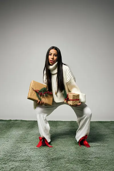 She balances elegantly in a playful pose while holding beautifully wrapped presents. — Stock Photo