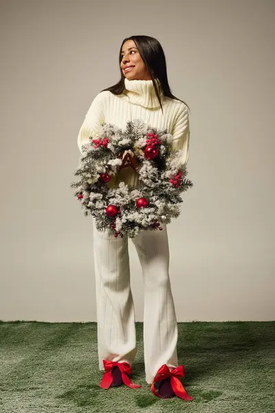 A cheerful young woman wears a festive wreath adorned with holiday decorations. — Stock Photo