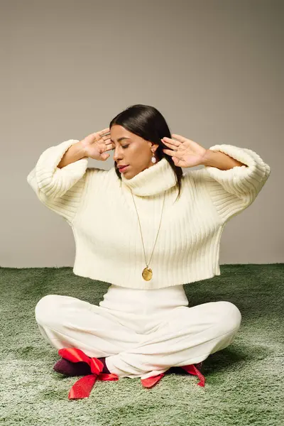 The young woman poses elegantly, exuding tranquility while dressed in cozy attire. — Stock Photo