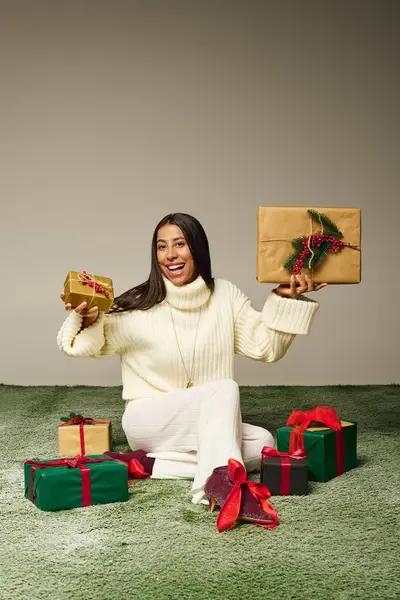 A joyful young woman is smiling while surrounded by beautifully wrapped gifts during festivities. — Stock Photo
