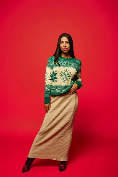 A stylish young woman dressed in a festive sweater and long skirt stands confidently on display. — Stock Photo
