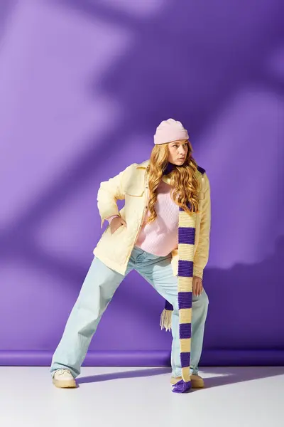 A young beautiful woman confidently poses in a cozy outfit featuring a scarf and beanie. — Stock Photo