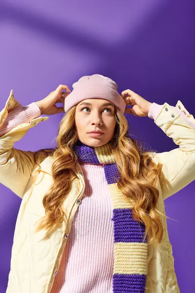 A fashionable young woman adjusts her beanie while showcasing her winter outfit with confidence. — Stock Photo