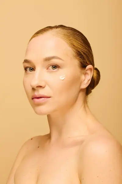 The young beautiful plus size woman gently with cream on her cheek while facing the camera. — Stock Photo
