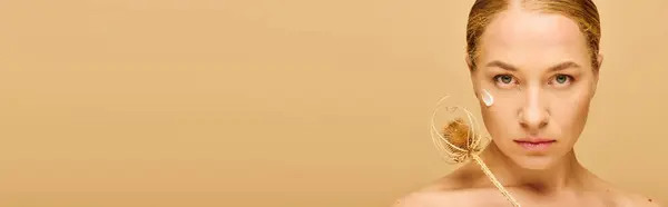 La joven de aspecto natural aplica con confianza su cuidado de la piel, irradiando belleza. - foto de stock