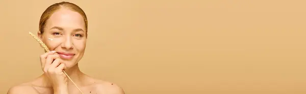A young beautiful plus size woman gracefully holds a piece of wheat while smiling gently. — Stock Photo