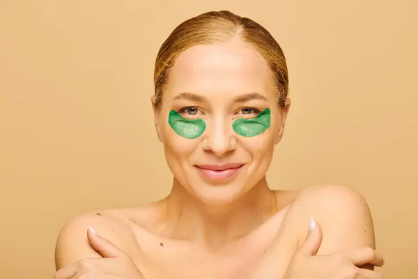 A joyful woman with eye patches smiles confidently while embracing her natural beauty and self care. — Stock Photo