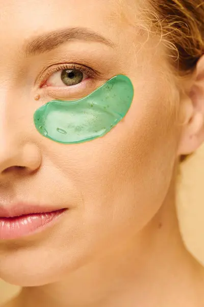 A woman applies a vibrant green eye mask for rejuvenation while relaxing at home. — Stock Photo