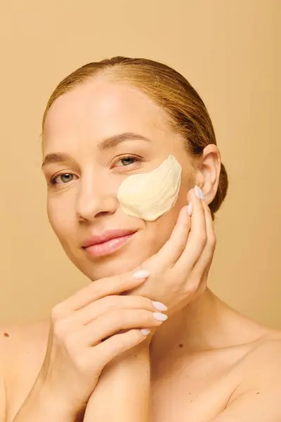 A young beautiful woman smiles while applying a soothing mask to her face, embracing self care. — Stock Photo